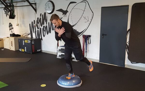 Dennis Meyerrose balanciert einbeinig auf einem Bosu-Ball. Bei dieser Übung werden Koordination und Gleichgewicht geschult sowie die seitliche Rumpfmuskulatur bei einer dem Golfschwung nachempfundenen Drehung des Oberkörpers